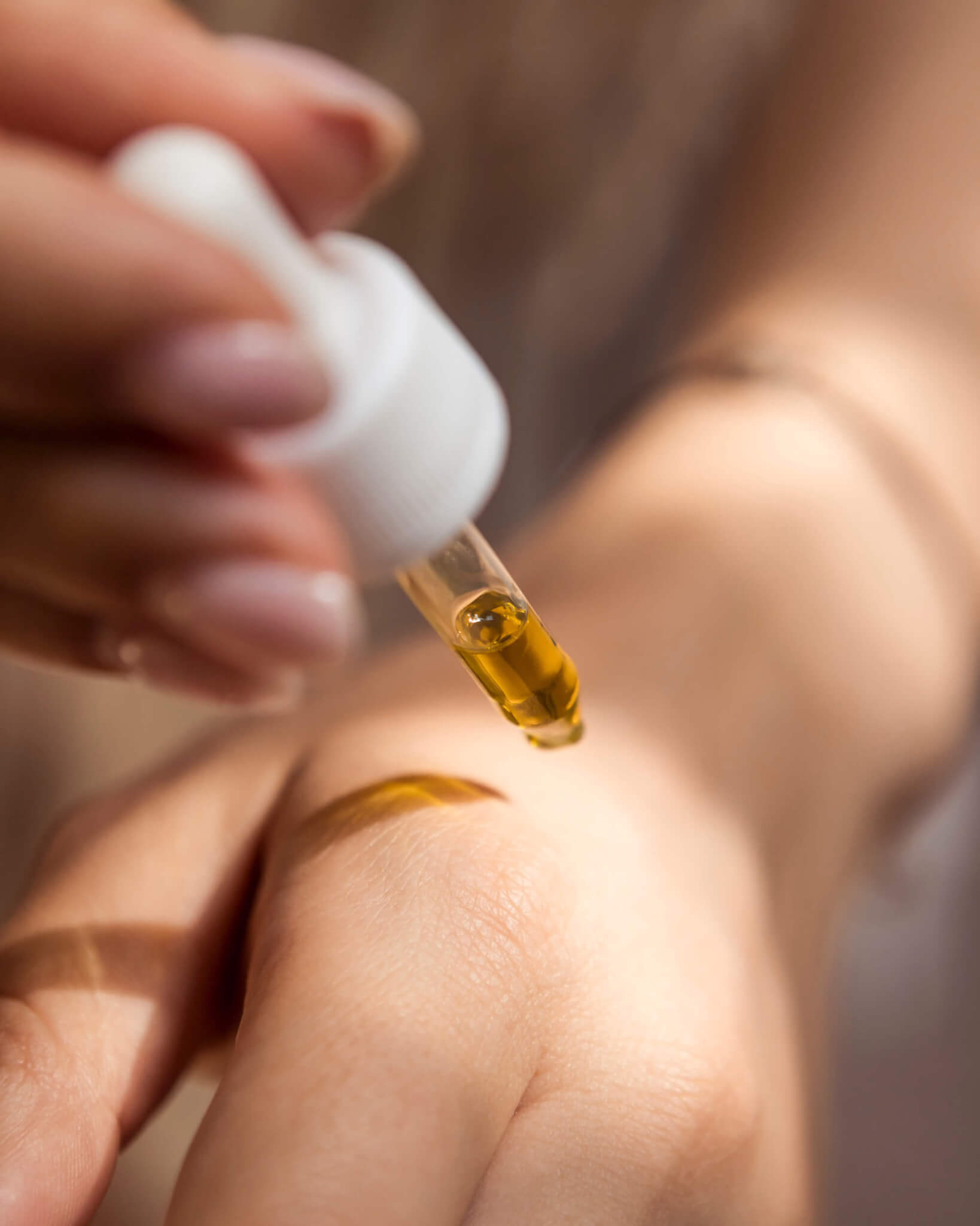 Nature's Canopy House A close-up of a person applying oil from a dropper onto the back of their hand, sourced from Nature's Canopy House, a premier dispensary in Mississauga. Dispensary In Mississauga