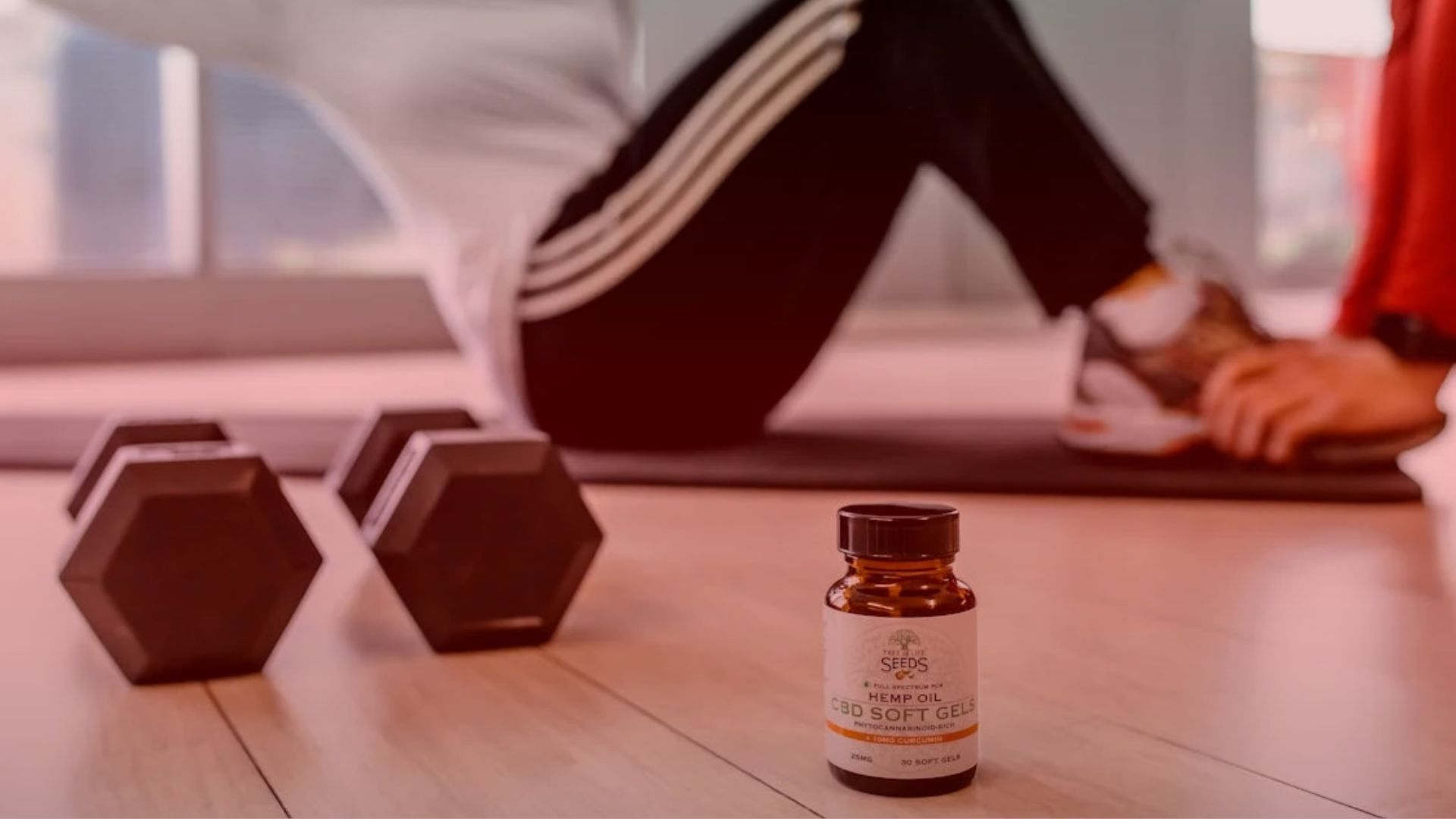 Nature's Canopy House A person exercising on a mat indoors with two dumbbells and a bottle labeled "CBD Soft Gel" on the floor in the foreground. Dispensary In Mississauga