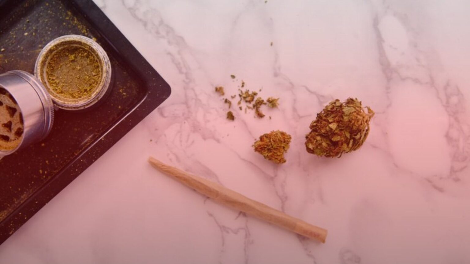 Nature's Canopy House A cannabis pre-roll rests beside a vibrant bud, a grinder, and a sleek tray on the marble surface. Dispensary In Mississauga