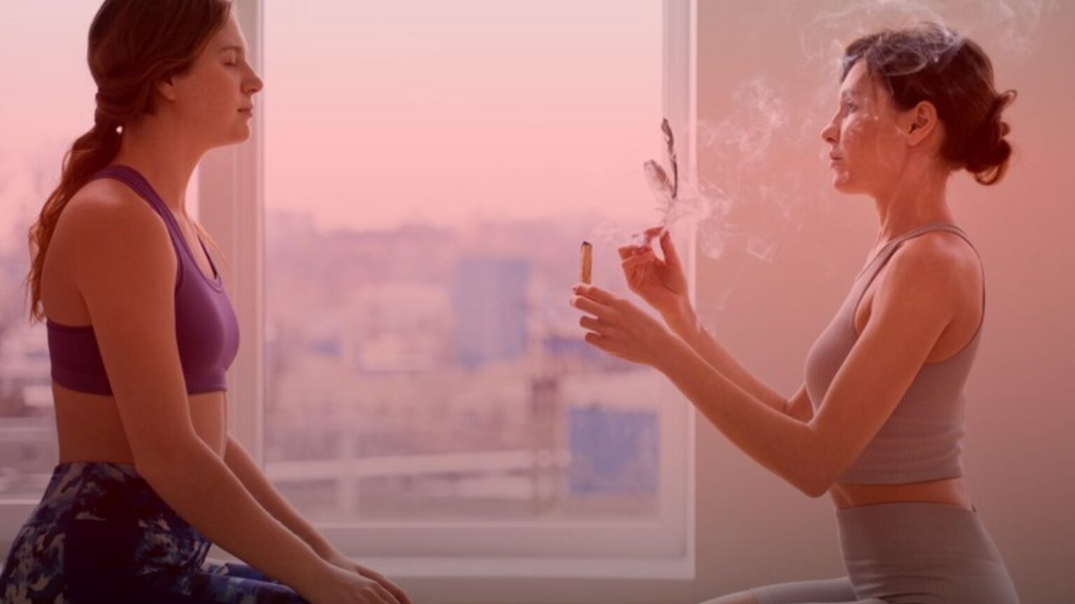 Nature's Canopy House Two women are seated face to face indoors; one holds a smoking incense stick while the other meditates with her eyes closed. Both wear athletic wear, merging the calming essence of cannabis and meditation to enhance their mindfulness experience. Dispensary In Mississauga