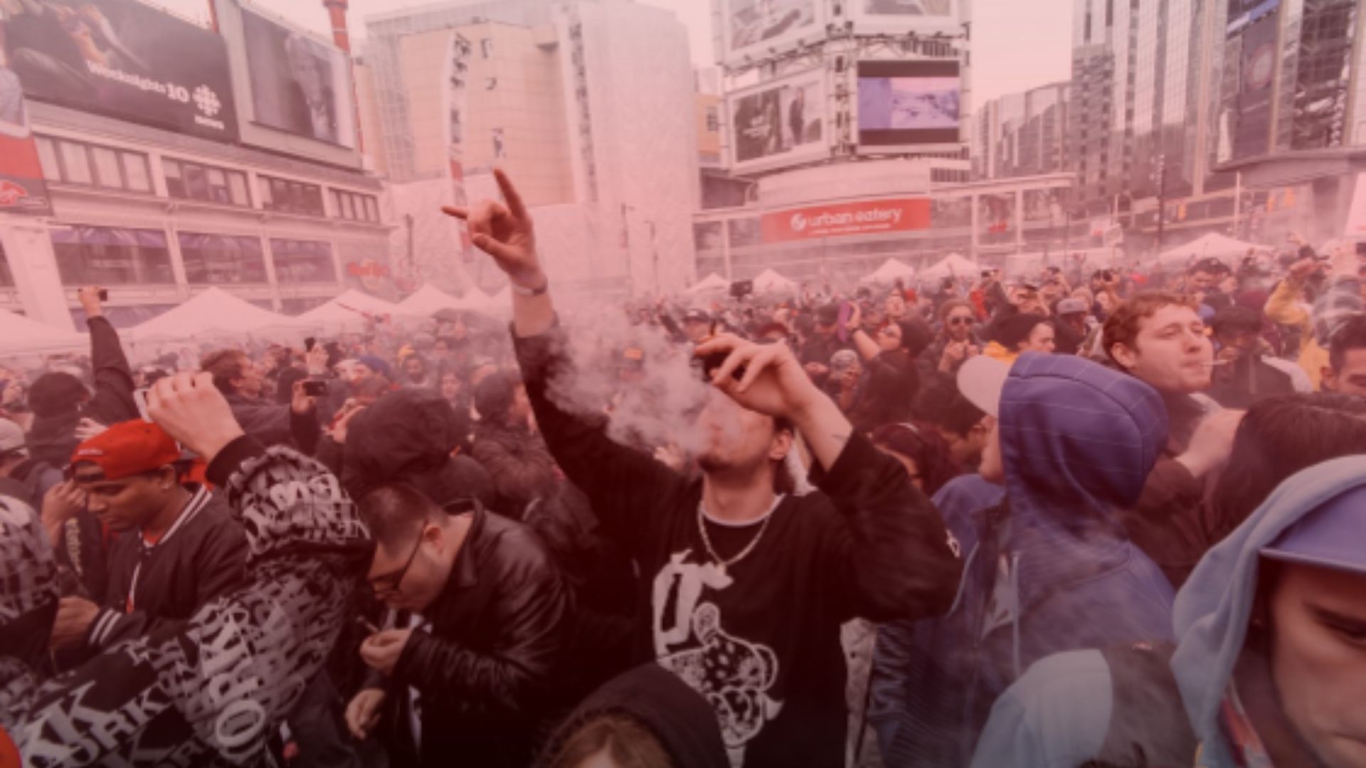 Nature's Canopy House A crowd of people in an urban square, many vaping, with surrounding buildings and advertisements in the background. Dispensary In Mississauga