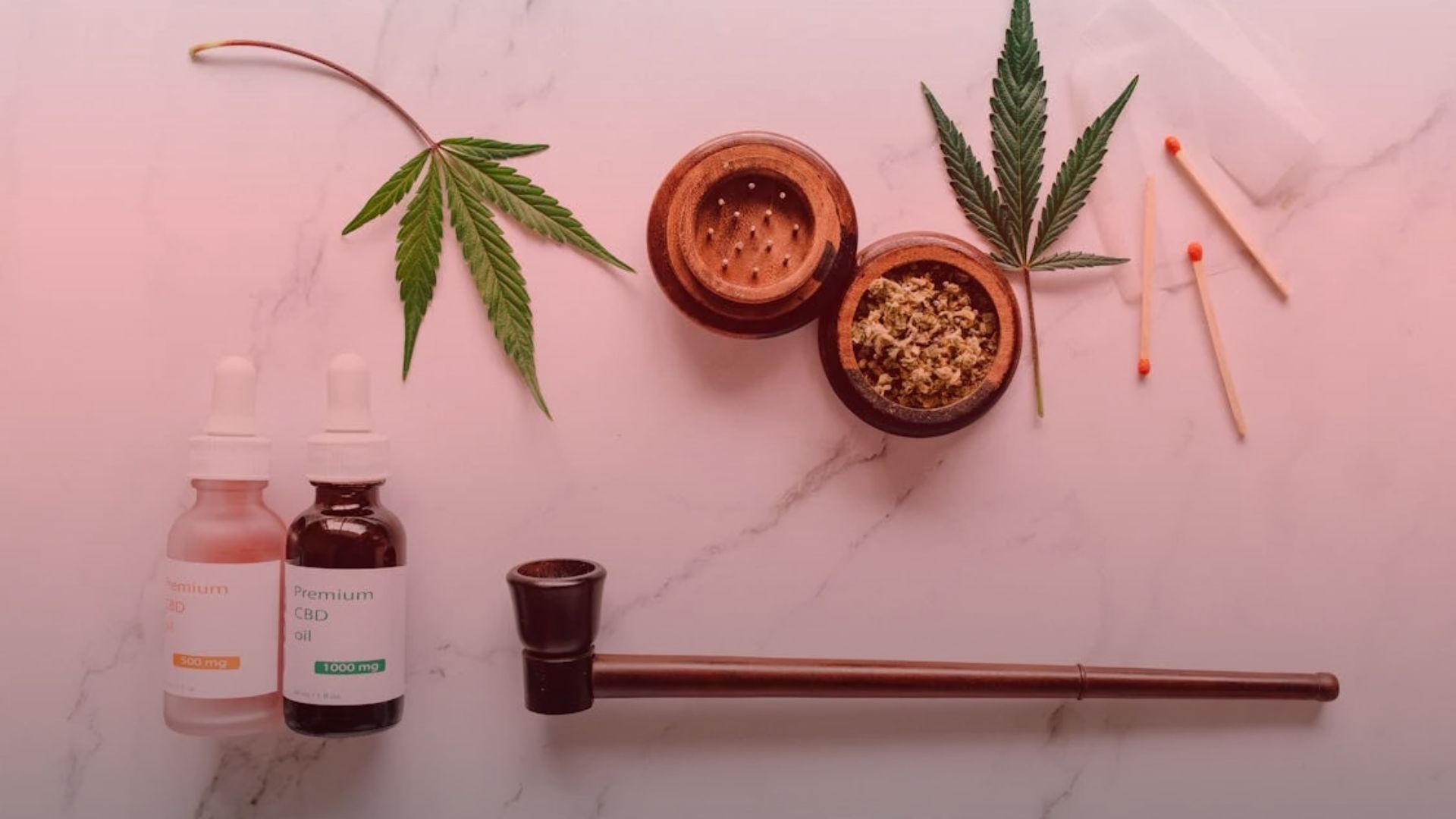 Nature's Canopy House Innovative cannabis products like CBD oil bottles, a wooden grinder, and a pipe are artfully arranged alongside cannabis leaves and matches on a marble surface. Dispensary In Mississauga