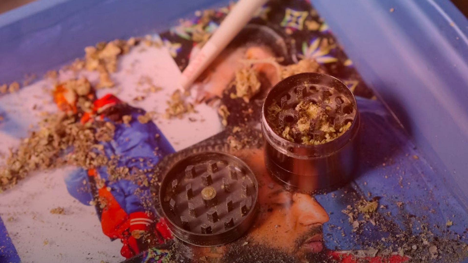 Nature's Canopy House A grinder with quality cannabis residue rests on a colorful tray, showcasing a blurred image of a person in a blue jacket. Dispensary In Mississauga