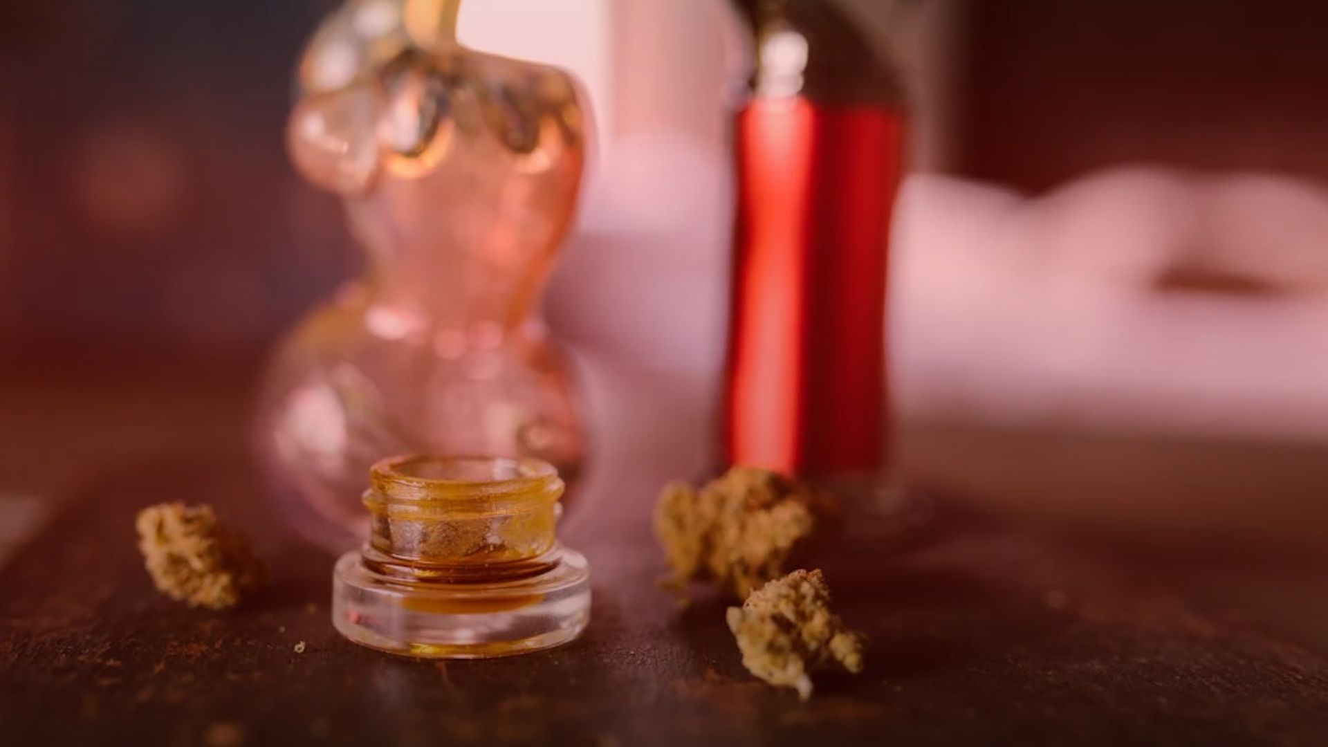 Nature's Canopy House A glass jar showcasing potent cannabis concentrate sits on the table, surrounded by lush cannabis buds. In the background, two decorative glass bottles add a touch of elegance to the scene. Dispensary In Mississauga